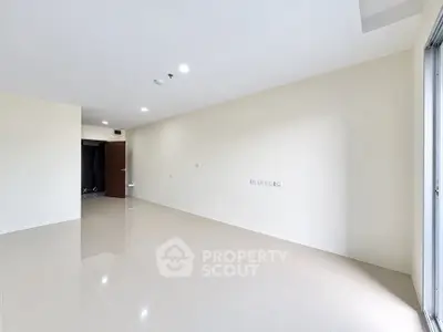 Spacious empty room with glossy tiled flooring and open door, perfect for customization.