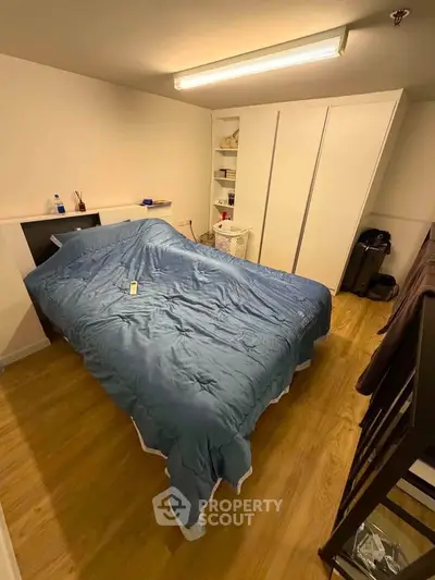 Cozy bedroom with wooden flooring and ample storage space, featuring a comfortable bed and modern lighting.