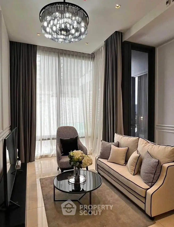 Elegant living room with modern chandelier, cozy sofa, and floor-to-ceiling windows for natural light.