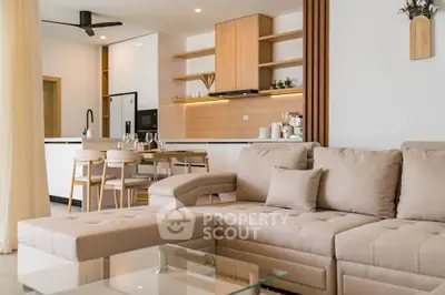 Modern open-layout living room with stylish kitchen and cozy beige sofa.