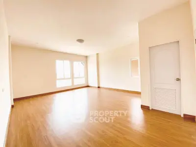 Spacious empty room with wooden flooring and large windows