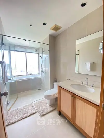 Modern bathroom with glass shower and large window offering natural light.