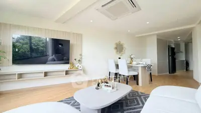 Modern living room with stylish decor and open dining area, featuring a large wall-mounted TV and sleek furniture.