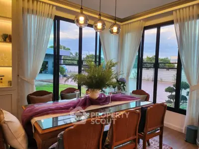 Elegant dining room with large windows and garden view, featuring stylish lighting and decor.