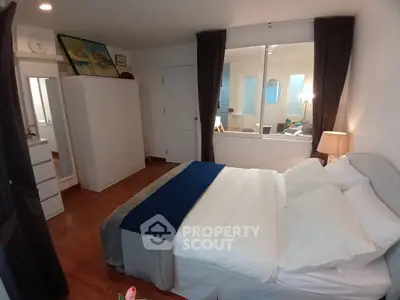 Cozy bedroom with modern decor and large window overlooking living area, perfect for relaxation.