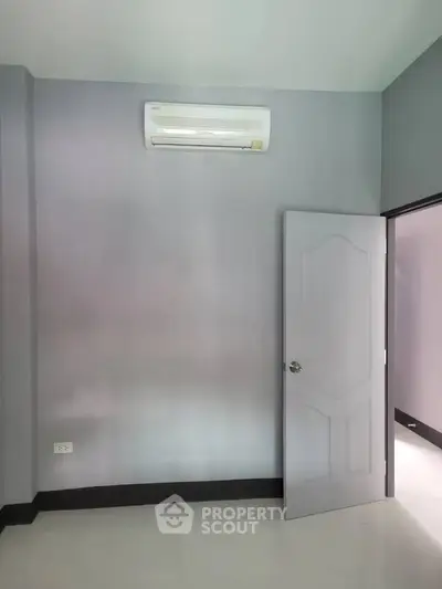 Minimalist room with air conditioning and open door, showcasing sleek gray walls and modern design.