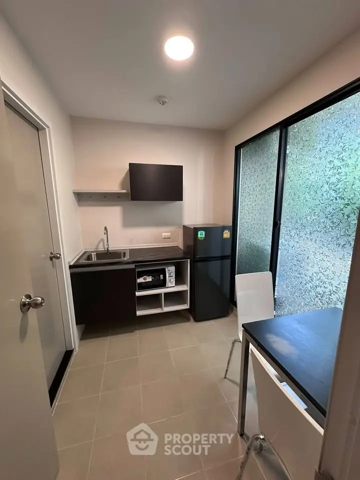 Modern compact kitchen with sleek cabinetry and dining area in a cozy apartment.