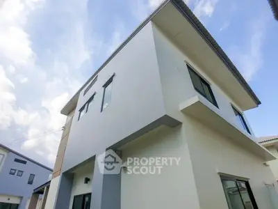 Modern two-story house with sleek design and large windows under a clear blue sky.