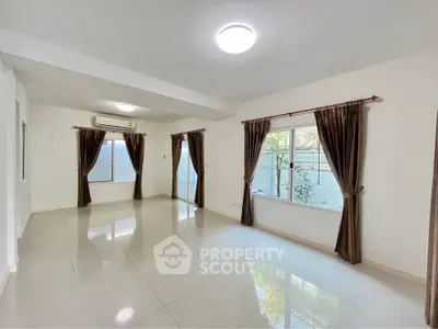 Spacious living room with large windows and elegant curtains, perfect for natural light.