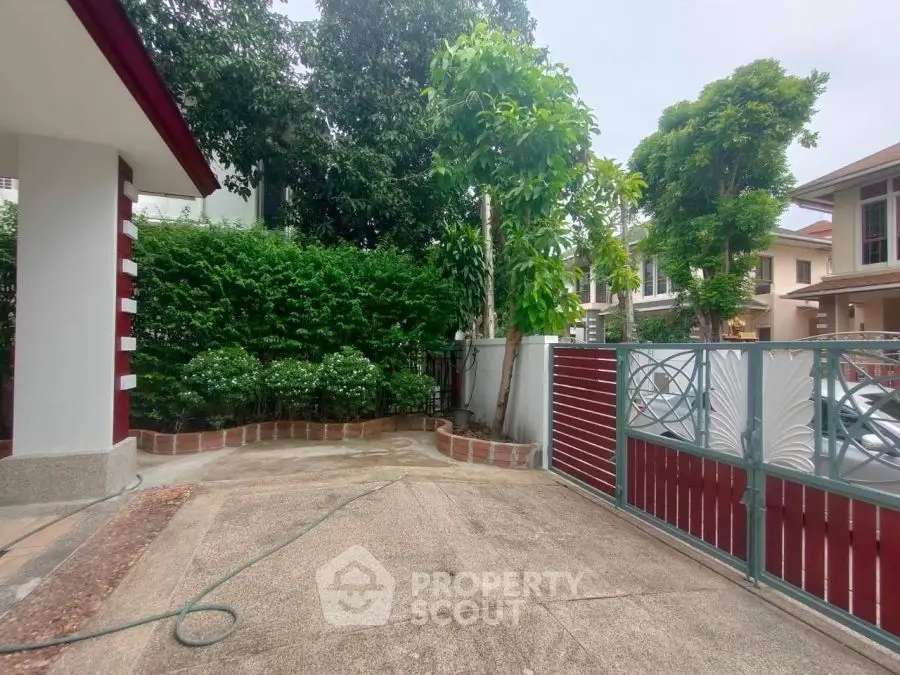 Charming residential driveway with lush greenery and modern gate design.