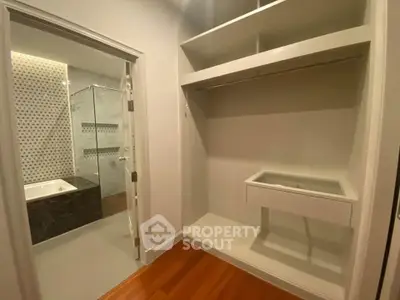 Spacious walk-in closet with adjacent modern bathroom featuring a glass shower and bathtub.