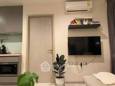 Modern living room with wall-mounted TV and air conditioning, featuring sleek kitchen appliances.