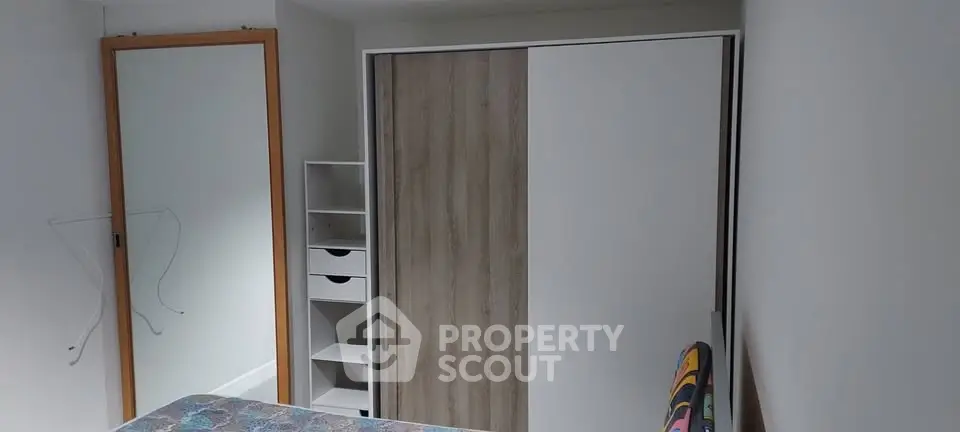 Cozy bedroom with modern wardrobe and mirror, perfect for comfortable living.
