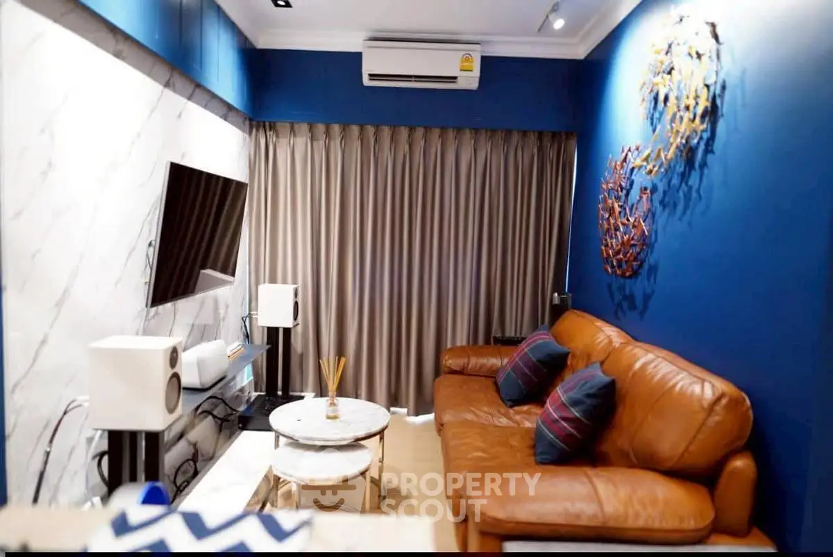Stylish living room with leather sofa, modern decor, and wall-mounted TV in a cozy apartment.