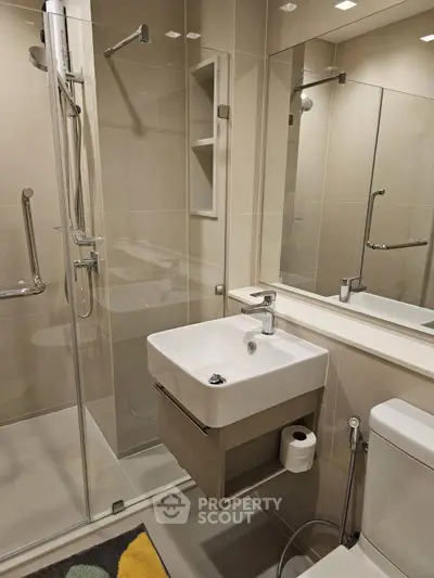 Modern bathroom with glass shower and sleek fixtures in contemporary apartment.