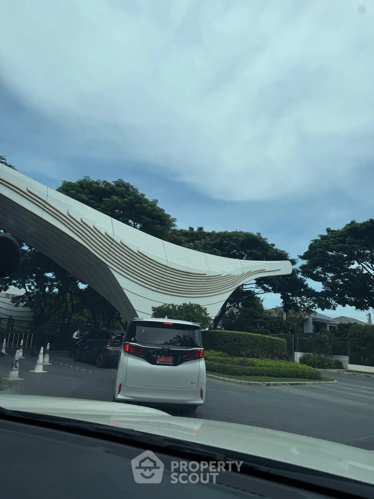Modern architectural entrance with sleek design and lush greenery.