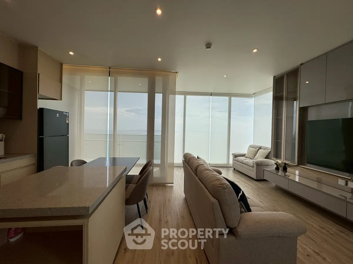 Luxurious open-plan living room with stunning ocean view, modern furniture, and sleek kitchen design.