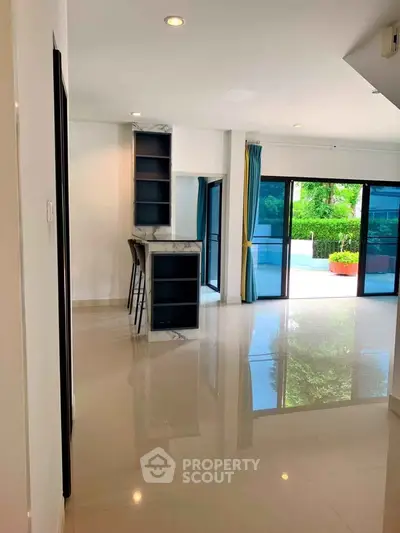 Spacious modern living room with glossy floors and large windows opening to a garden view.