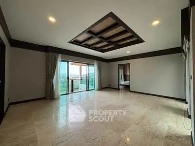 Spacious living room with elegant ceiling design and large windows offering scenic views.
