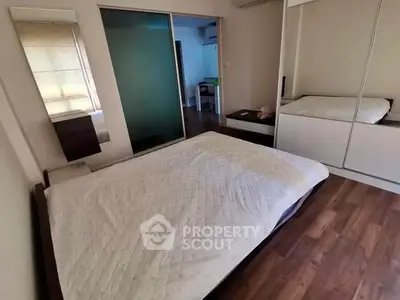 Spacious bedroom with wooden flooring and mirrored wardrobe