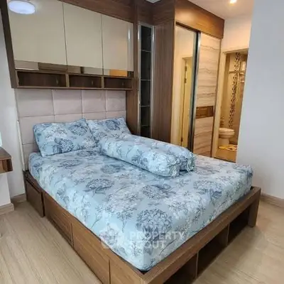 Cozy bedroom with floral bedding and modern wooden furniture, featuring a glimpse of an ensuite bathroom.