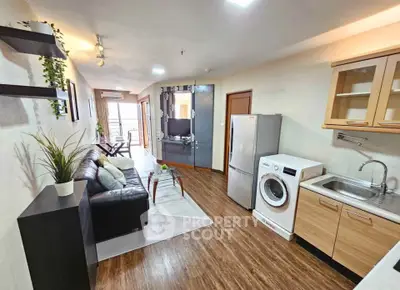 Modern open-plan living room with kitchen, featuring sleek appliances and stylish decor.