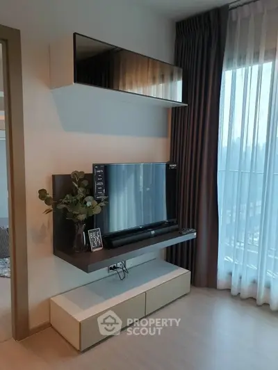 Modern living room with sleek TV unit and large window with sheer curtains