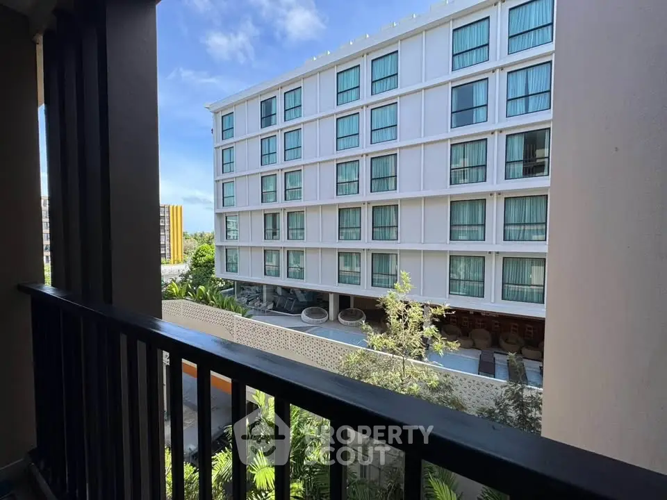 Modern apartment building with spacious balconies and lush greenery view.