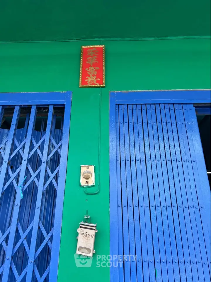Vibrant green and blue exterior with metal gate and doorbell, showcasing unique architectural style.