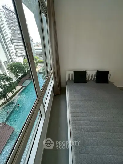 Modern bedroom with pool view, large window, and minimalist decor in urban setting.