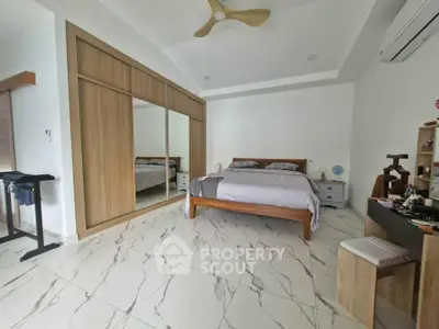 Spacious bedroom with modern design, featuring a large bed, mirrored wardrobe, and elegant tiled flooring.