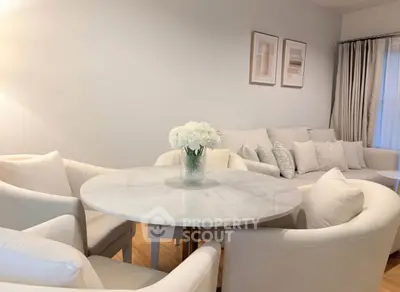 Elegant living room with white furniture and round marble table, perfect for modern living.