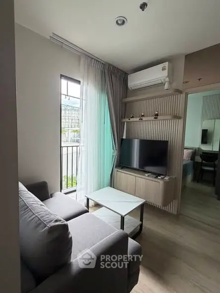 Modern living room with cozy sofa, TV, and natural light from large window in stylish apartment.