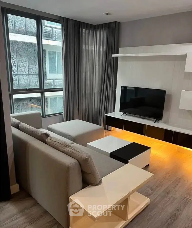 Modern living room with sleek furniture and large window in urban apartment.