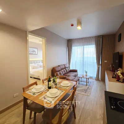 Modern open-plan living room with dining area and cozy bedroom view.