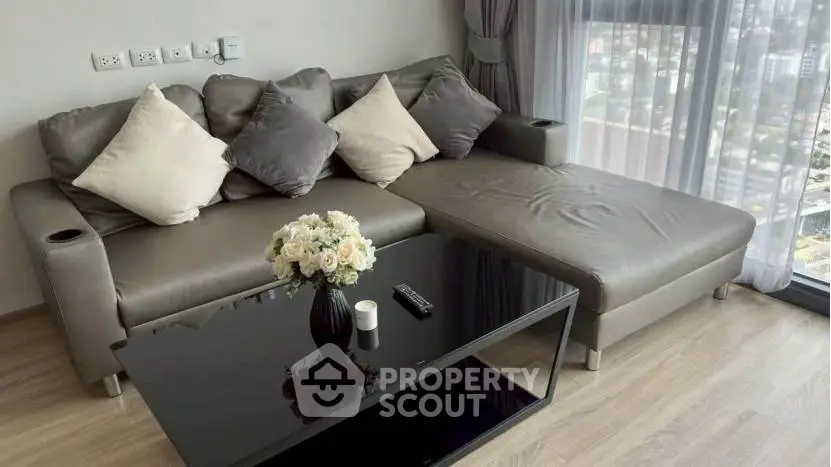 Modern living room with sleek sofa and city view through large windows.