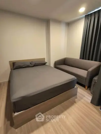 Cozy bedroom with modern decor featuring a comfortable bed and stylish sofa, perfect for relaxation.