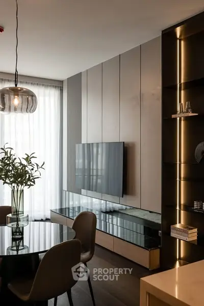 Modern living room with sleek TV setup and elegant dining area, featuring contemporary decor and natural light.