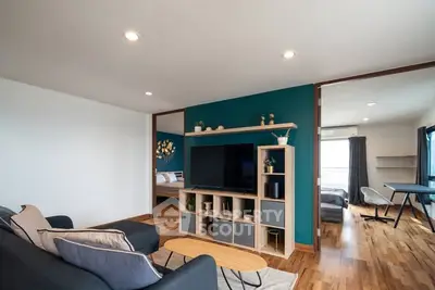 Modern living room with stylish decor and open view into bedroom and study area.