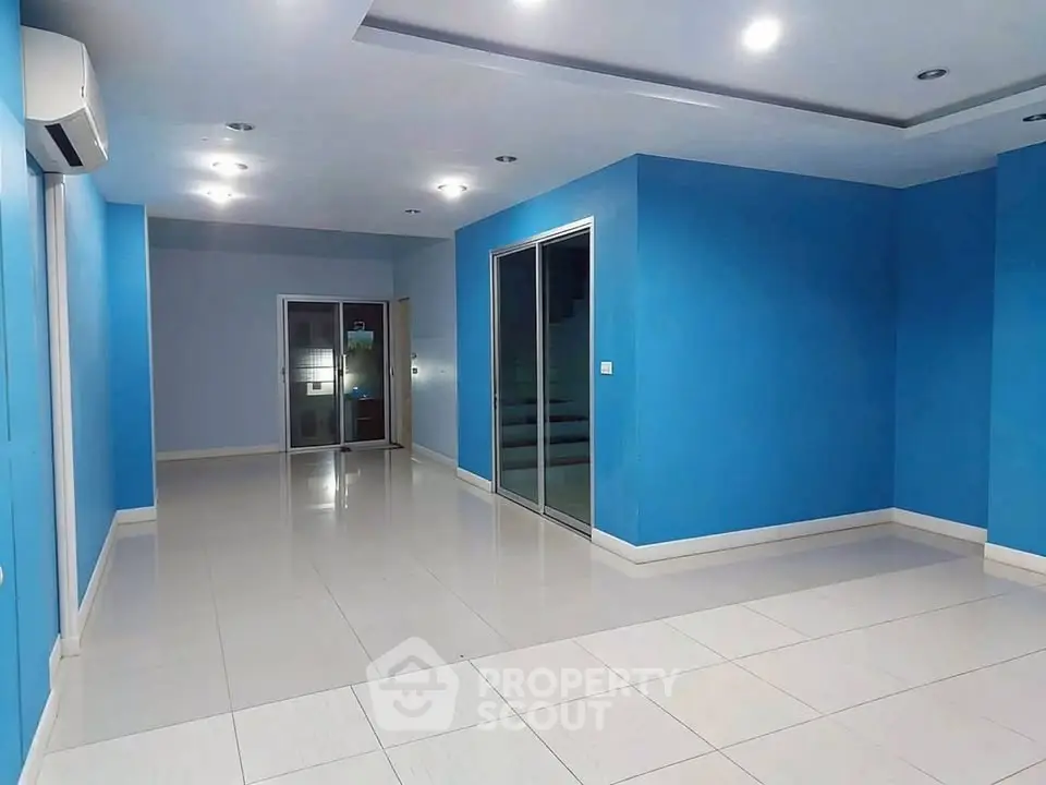 Spacious modern living room with blue walls and sleek tile flooring