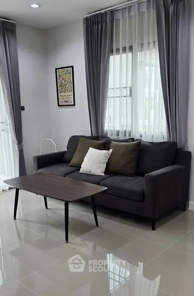 Modern living room with sleek sofa and stylish coffee table, featuring elegant curtains and polished tile flooring.