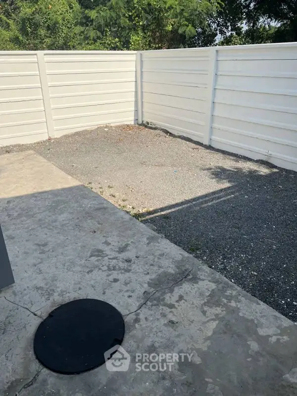Spacious outdoor area with privacy fence and gravel surface, ideal for customization.