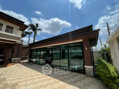Stunning modern home with glass garage and lush greenery under a bright blue sky.
