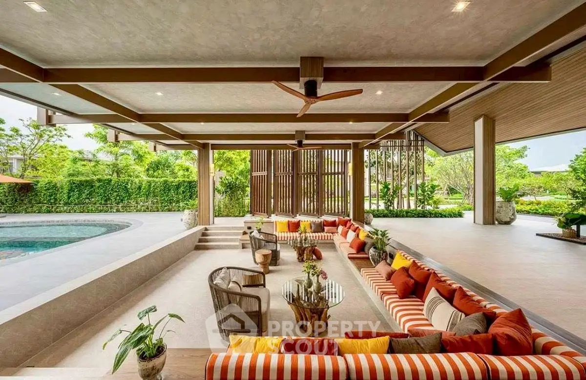 Luxurious open-air living space with pool and garden view, featuring stylish seating and modern design.