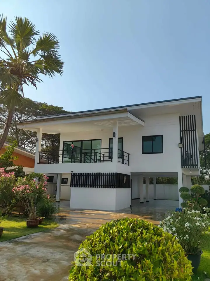 Modern two-story house with spacious balcony and lush garden