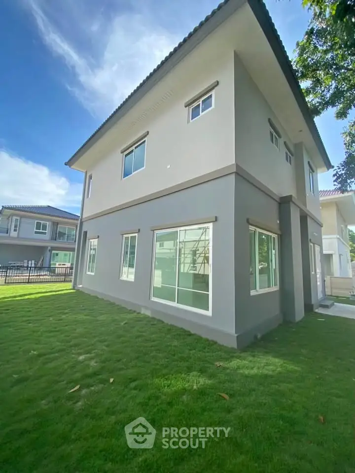 Modern two-story house with spacious lawn and large windows in a serene neighborhood.