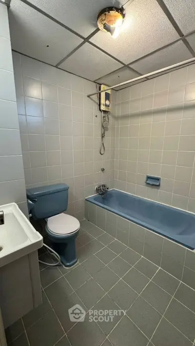 Spacious bathroom with vintage blue bathtub and matching toilet, ideal for renovation.
