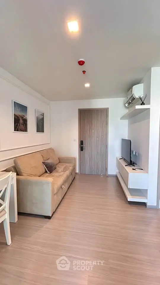 Modern living room with beige sofa, wall art, and flat-screen TV in a stylish apartment.
