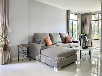 Spacious modern living room with large gray sectional sofa and floor-to-ceiling windows.