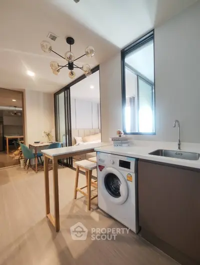 Modern kitchen with washing machine and stylish lighting in open layout apartment.